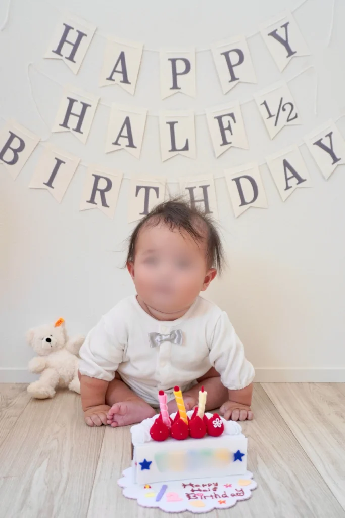 まだ支えがないと難しいおすわりに挑戦したハーフバースデー写真